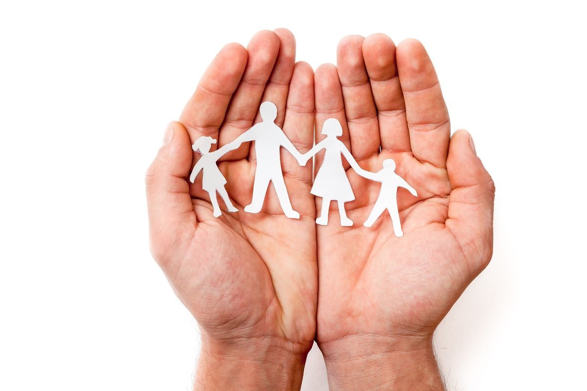 men's hands hold carved family silhouettes on a white background to protect the family, family security, family values